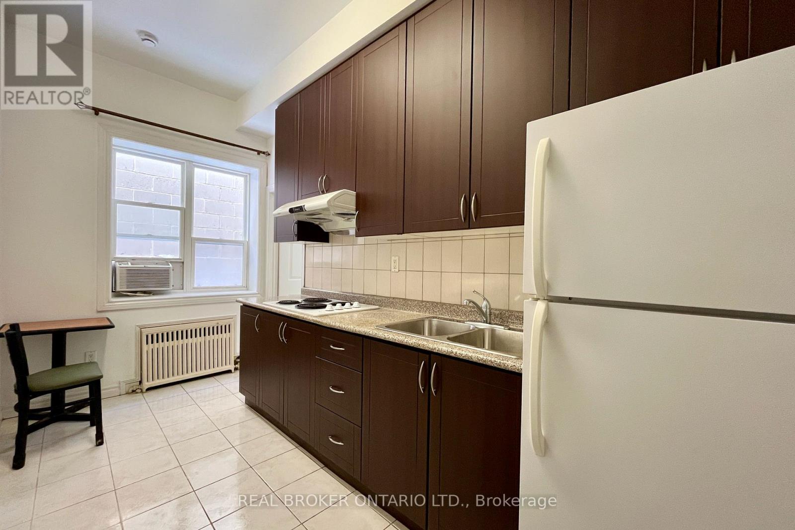 A kitchen with brown cabinets and a white refrigerator.