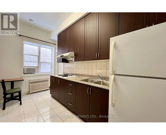 A kitchen with brown cabinets and a white refrigerator.