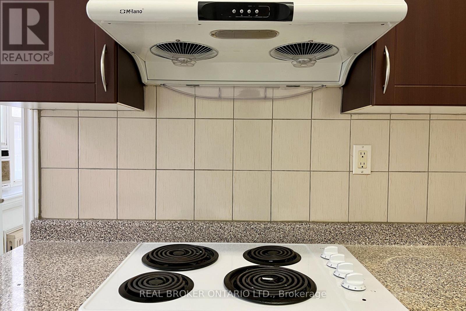 A white range hood with four burners below it.