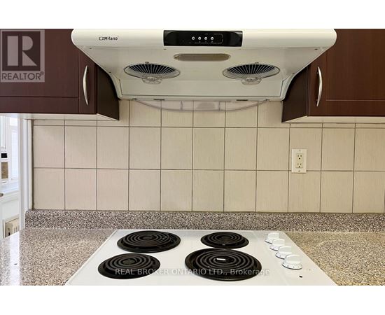 A white range hood with four burners below it.
