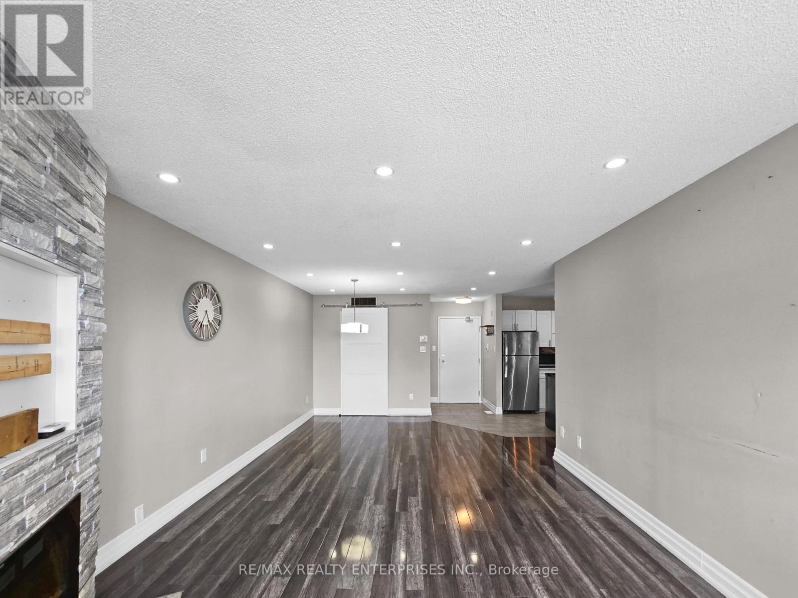 A spacious room with a stone fireplace and wood flooring.