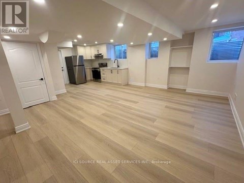 A spacious room with wooden flooring and a kitchen area.