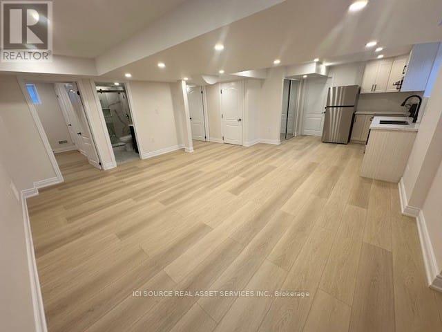 A spacious room with wooden flooring and white walls.
