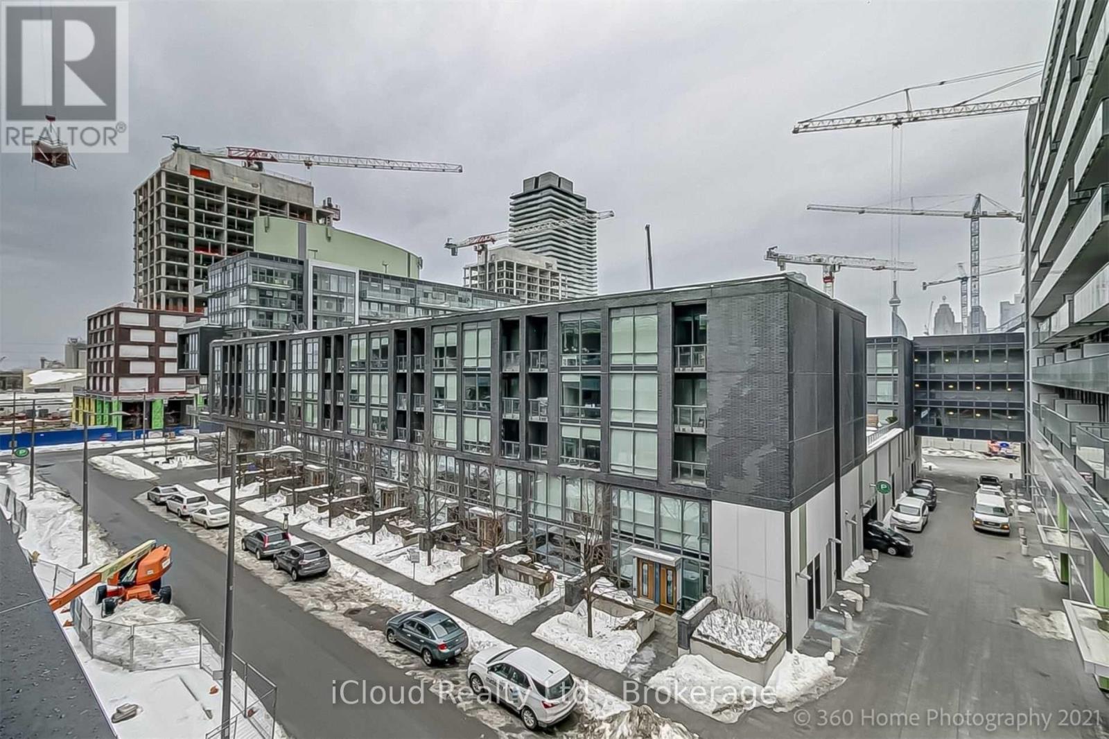 A construction site with a building under construction and several cranes in the background.