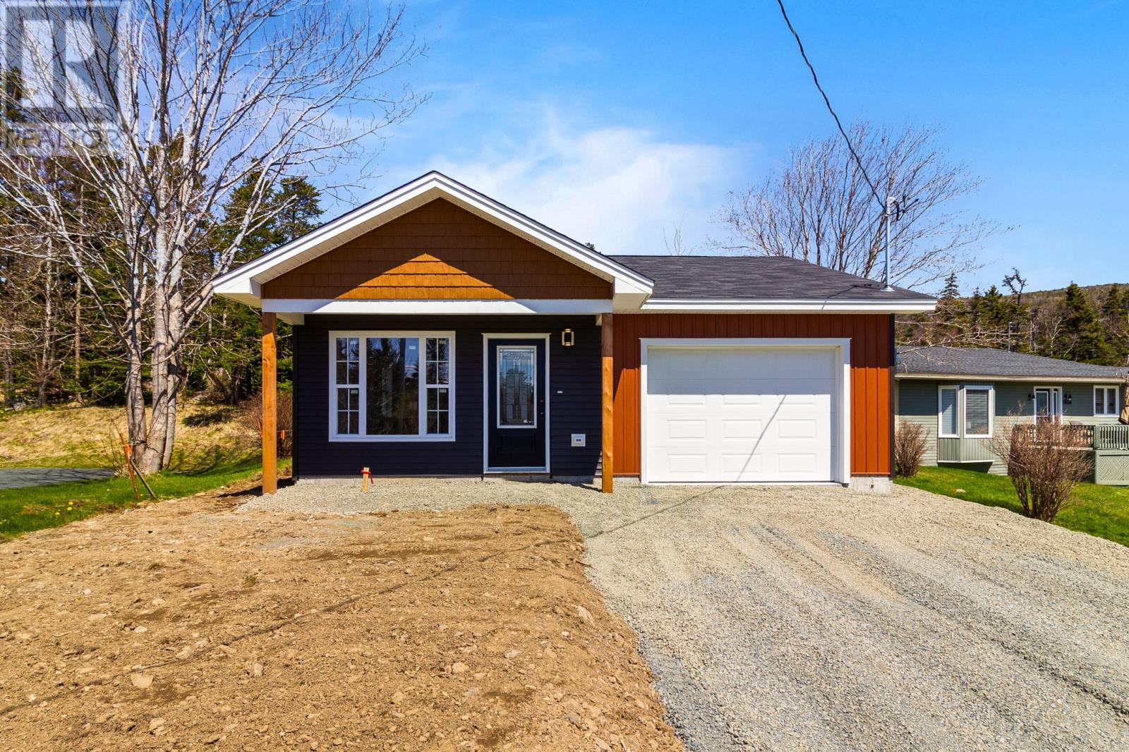 A two-car garage with a brown roof and black doors is situated in front of a house.