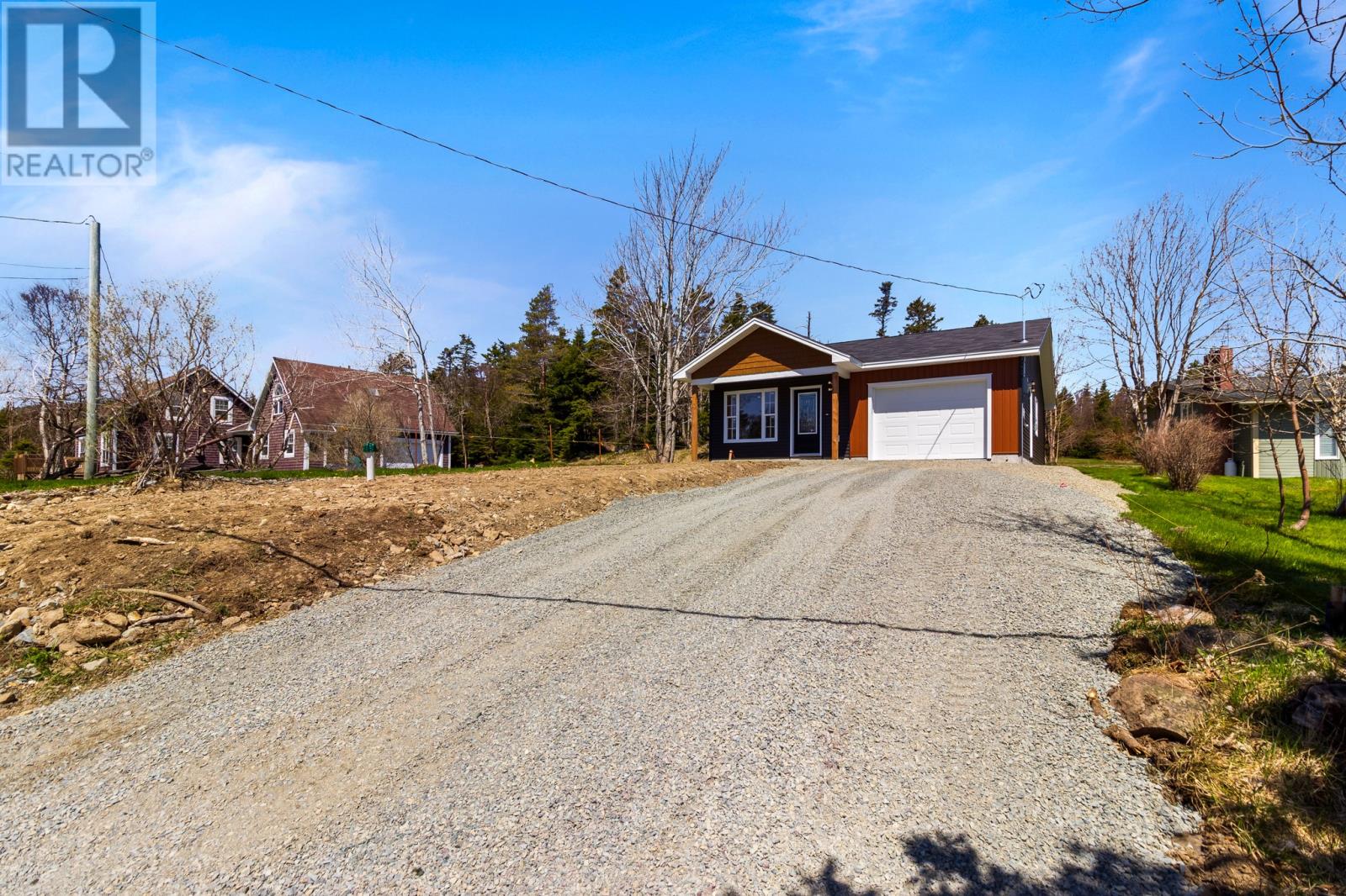 A gravel driveway leads to a two-story house with a garage.