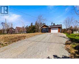 A gravel driveway leads to a two-story house with a garage.