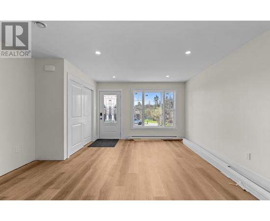 A spacious room with wooden floors and white walls.