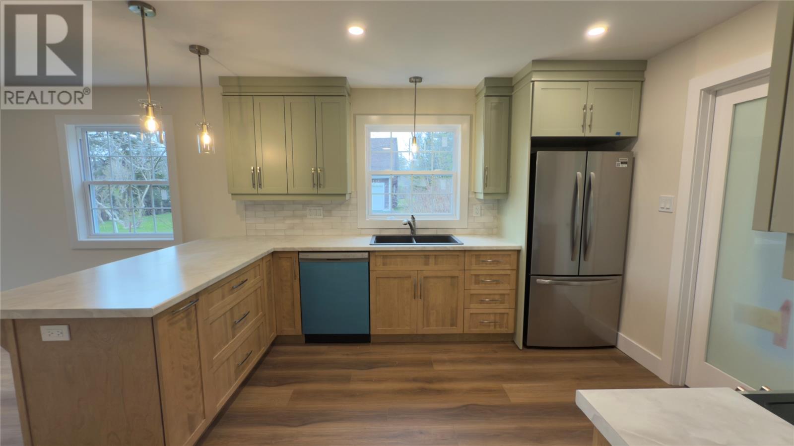 A kitchen with wooden cabinets and a stainless steel refrigerator.