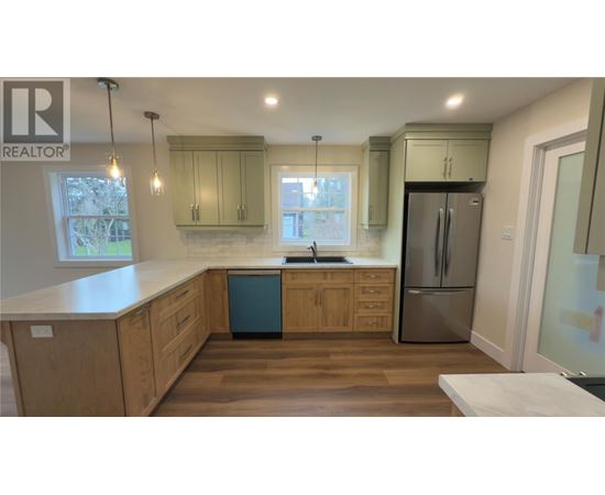 A kitchen with wooden cabinets and a stainless steel refrigerator.