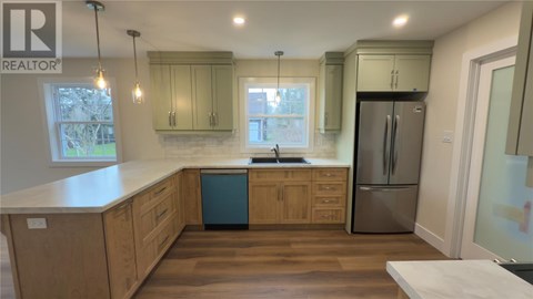 A kitchen with wooden cabinets and a stainless steel refrigerator.