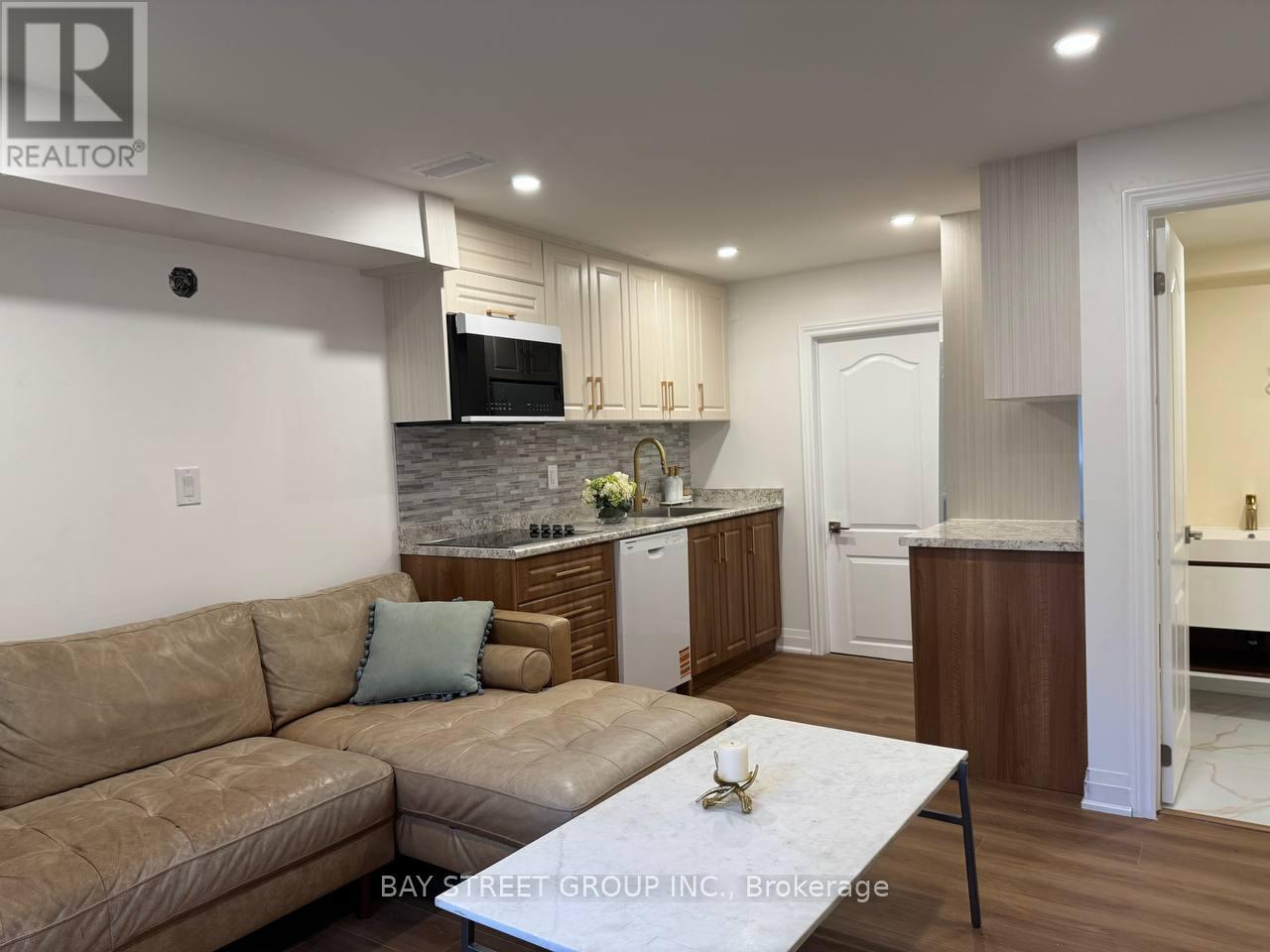 A well-lit living room with a couch, coffee table, and kitchen area in the background.