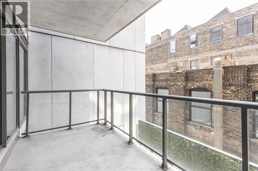 A balcony with a glass railing and a brick building in the background.