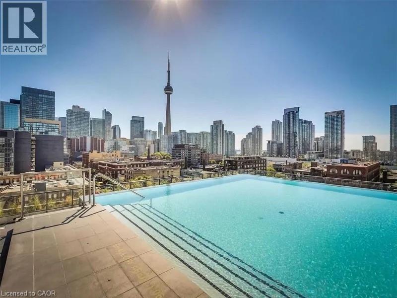 A swimming pool on a rooftop with a city skyline in the background.