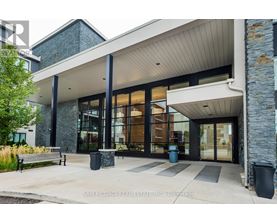 The front of a building with a glass entrance and a stone wall.