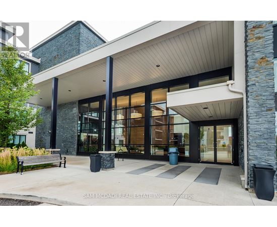 The front of a building with a glass entrance and a stone wall.
