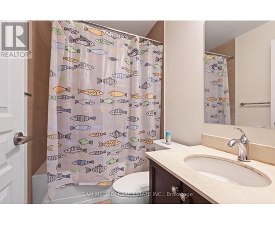 A bathroom with a shower curtain featuring fish patterns.