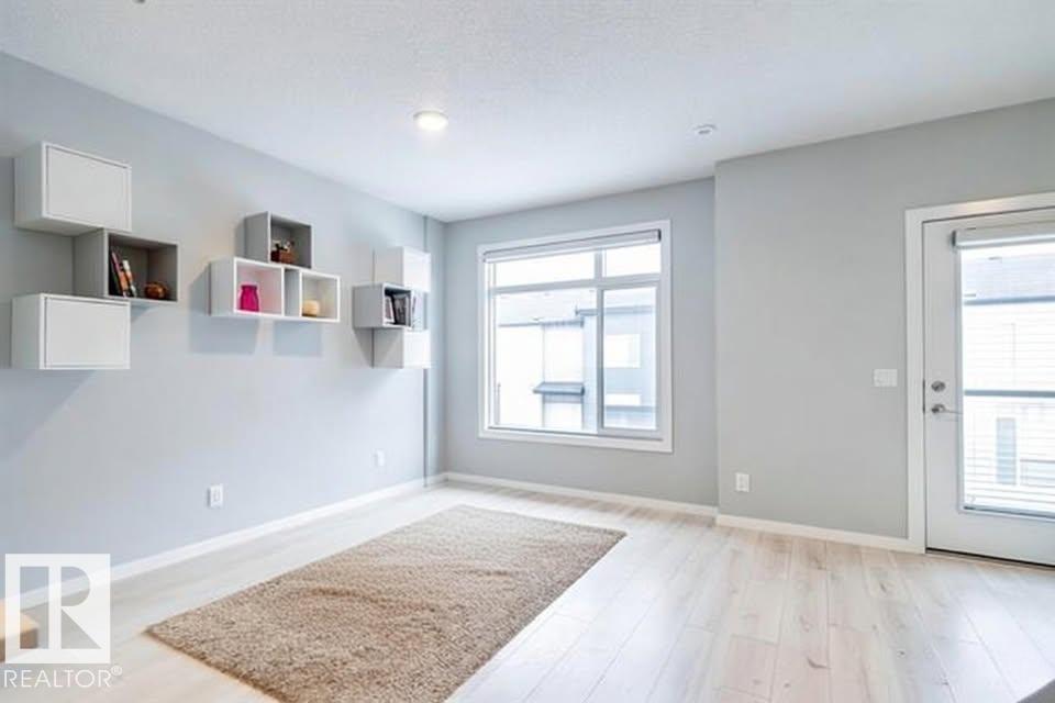 A room with a rug on the floor and a window with blinds.