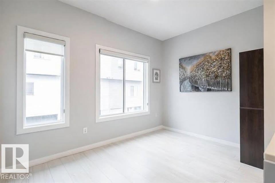 A room with a large painting on the wall and two windows.