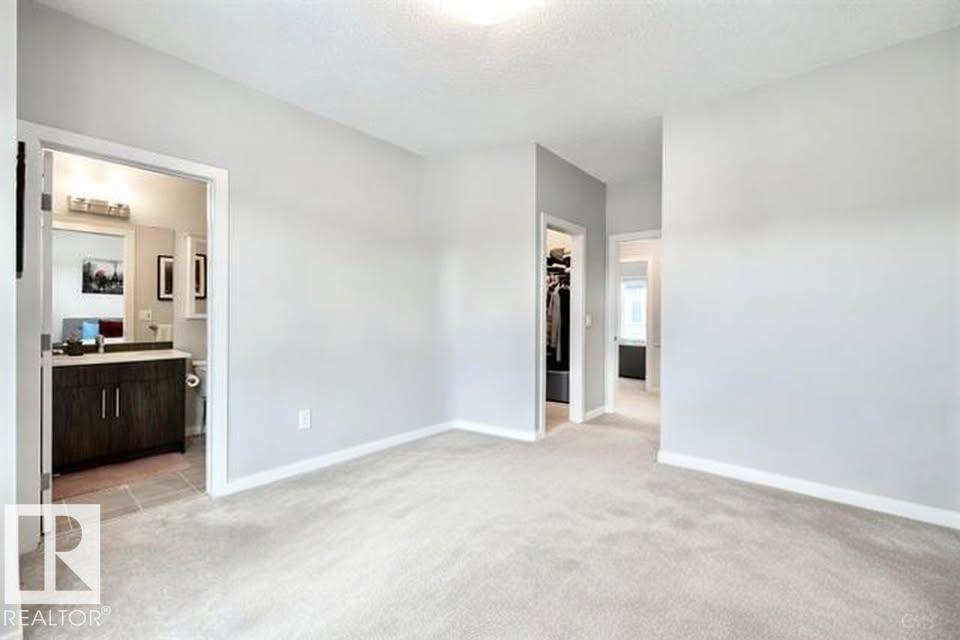 A spacious living room with a carpeted floor and a doorway leading to another room.
