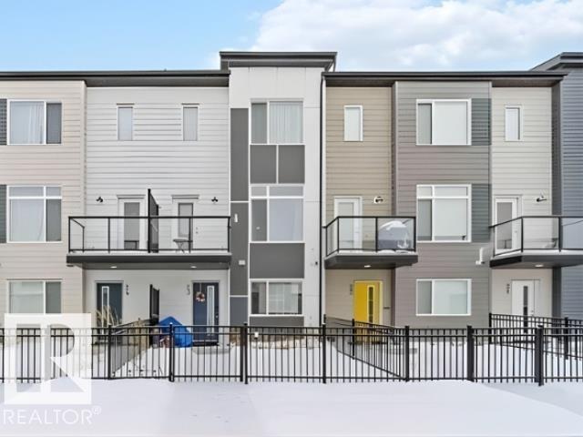 A modern apartment building with balconies and a fence in front.