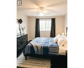 A bedroom with a bed, dresser, and ceiling fan.