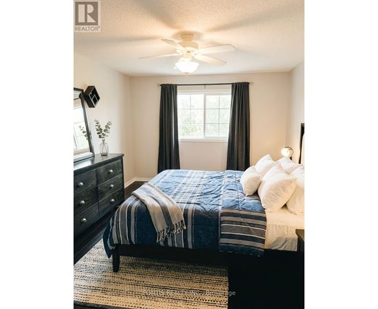 A bedroom with a bed, dresser, and ceiling fan.