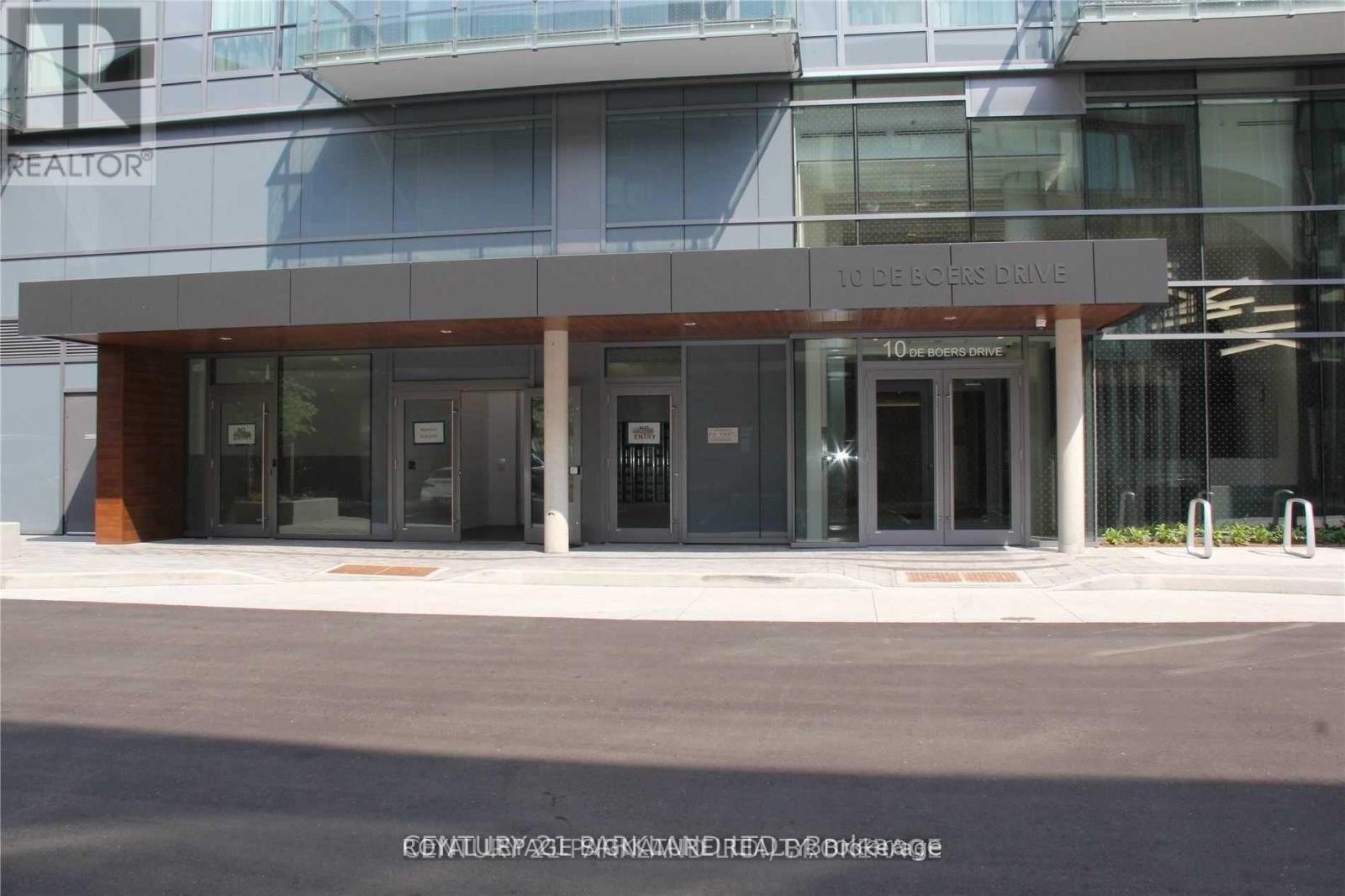 The front of a building with a glass facade and a brown awning.