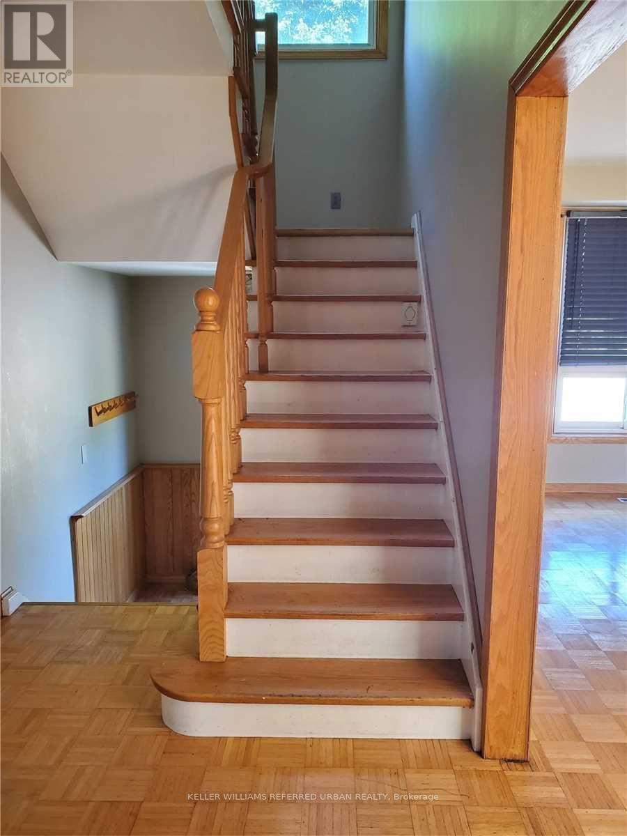 A wooden staircase with a white riser and a wooden handrail.