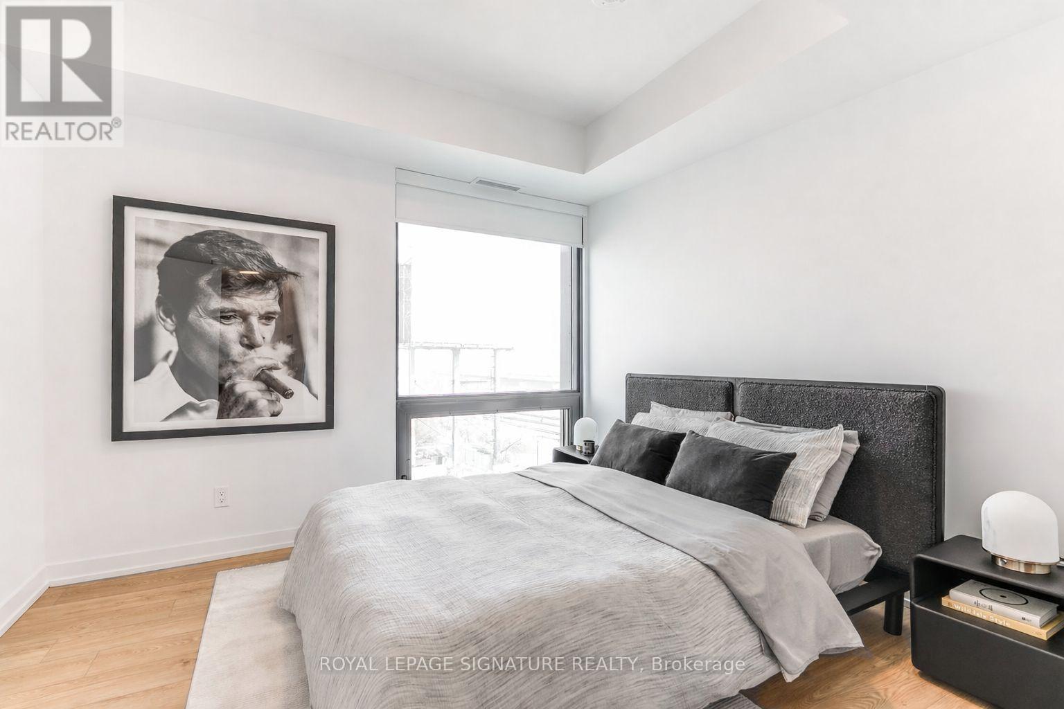 A bedroom with a large bed and a framed picture on the wall.