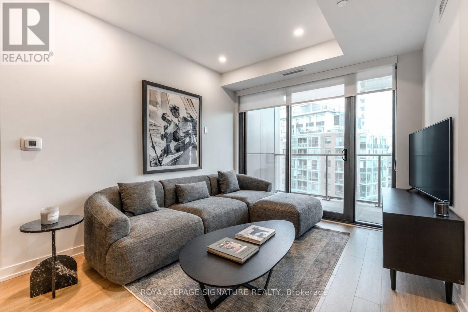 A living room with a grey couch and a painting on the wall.