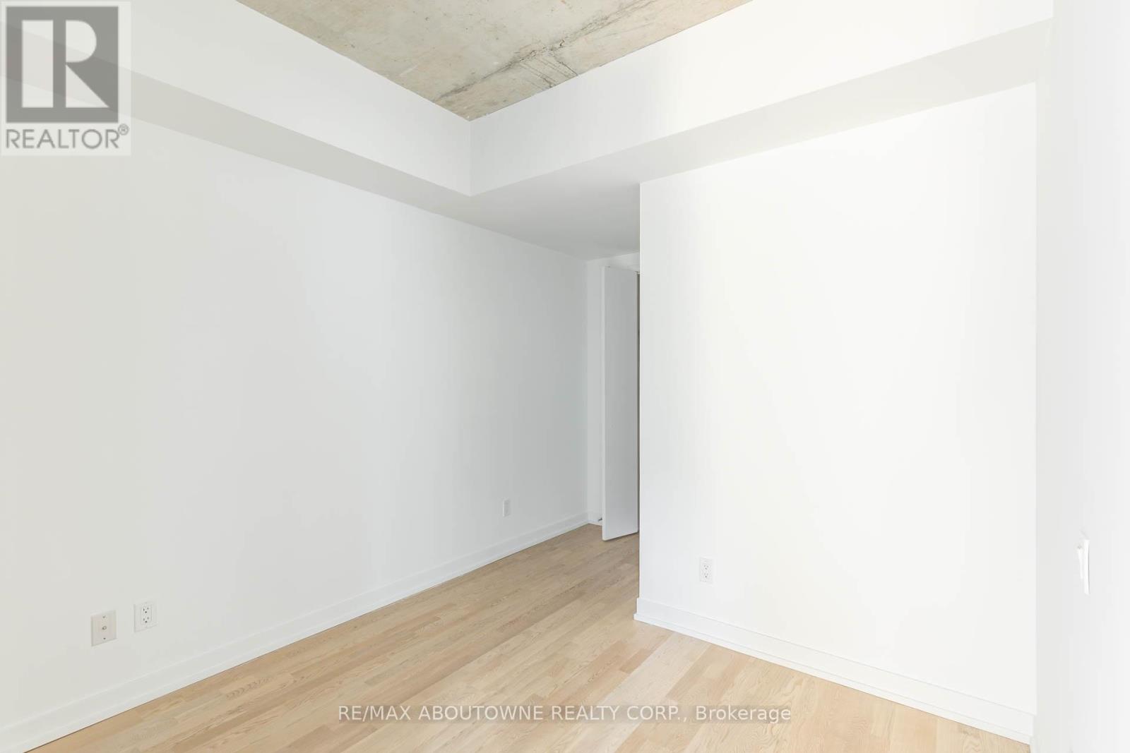 A spacious room with a wooden floor and white walls.
