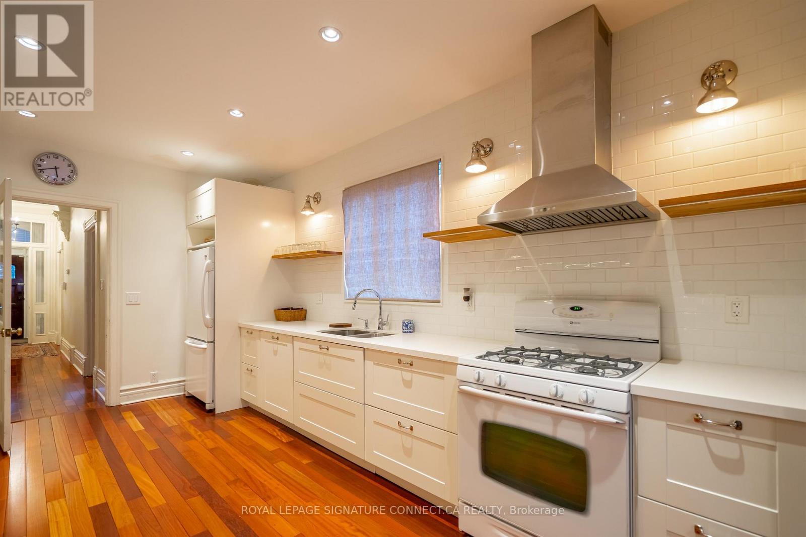 A modern kitchen with white cabinets and a stainless steel range hood.
