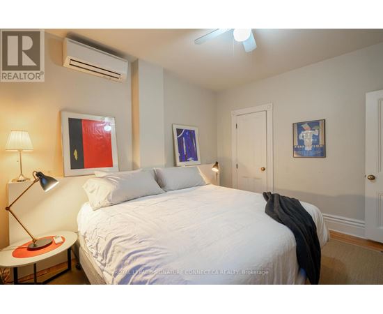 A bedroom with a white bed and a painting on the wall.