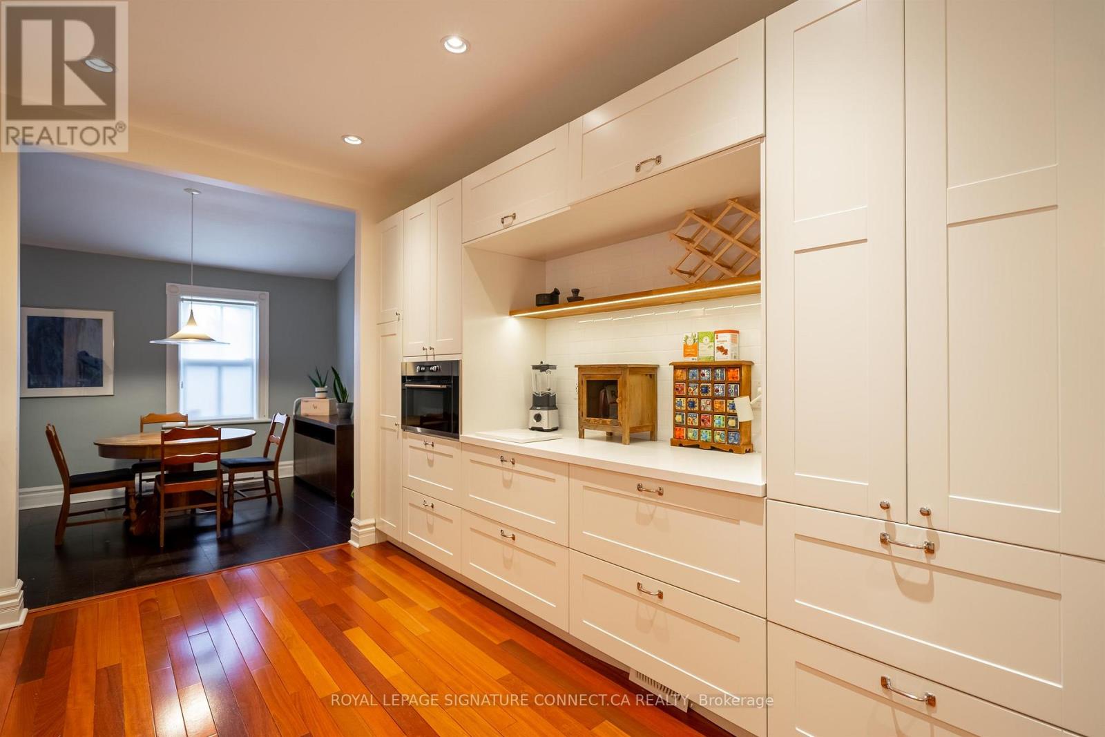 A kitchen with white cabinets and wooden floors.