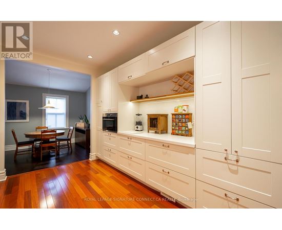 A kitchen with white cabinets and wooden floors.