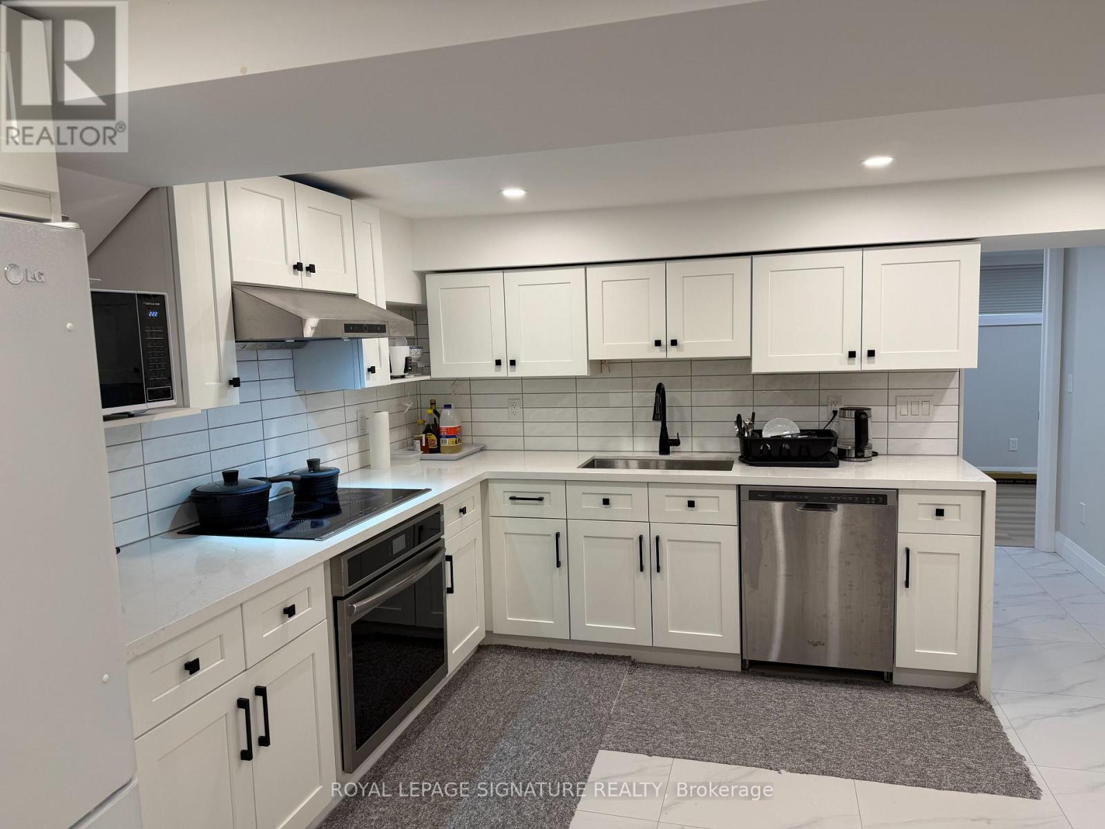 A white kitchen with a refrigerator, oven, and sink.