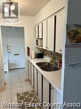 A kitchen with white cabinets and a black counter top.