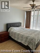 A bedroom with a bed, nightstand and a ceiling fan.