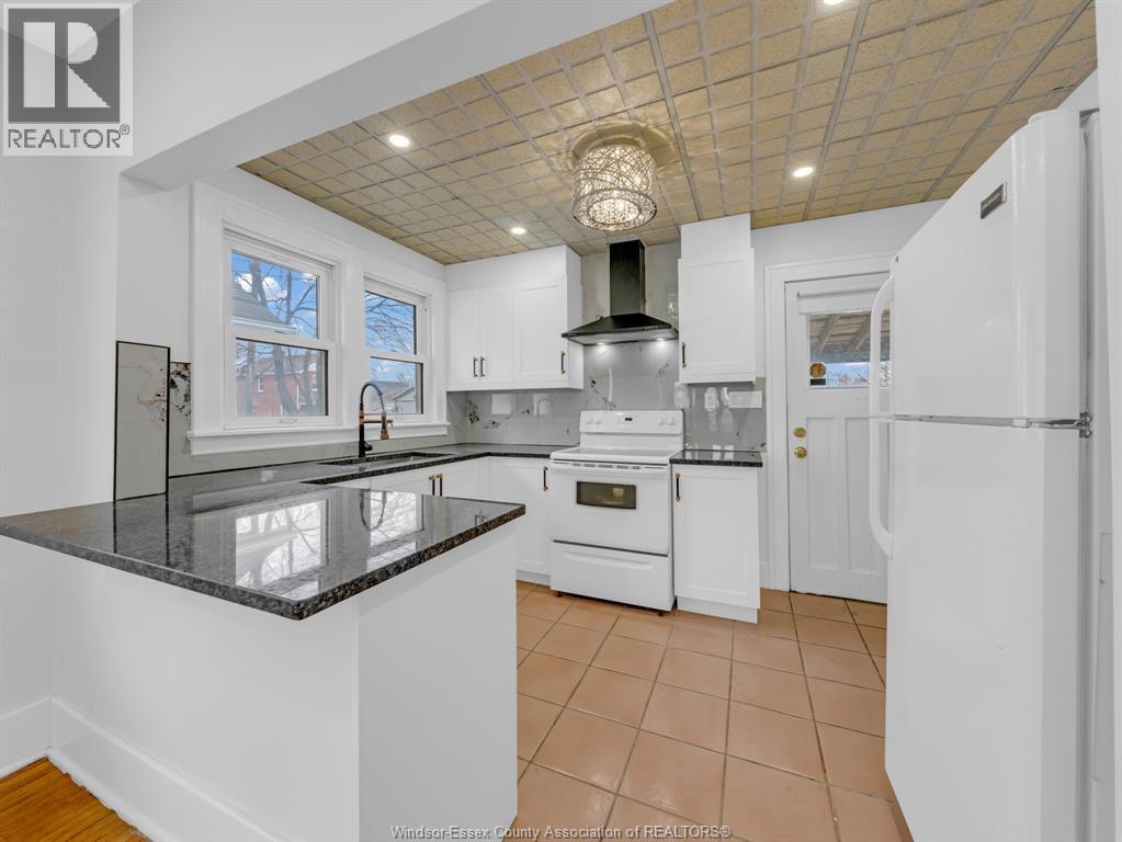 A kitchen with white cabinets and a black counter top.