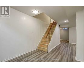 A spacious room with a staircase leading to the upper level.