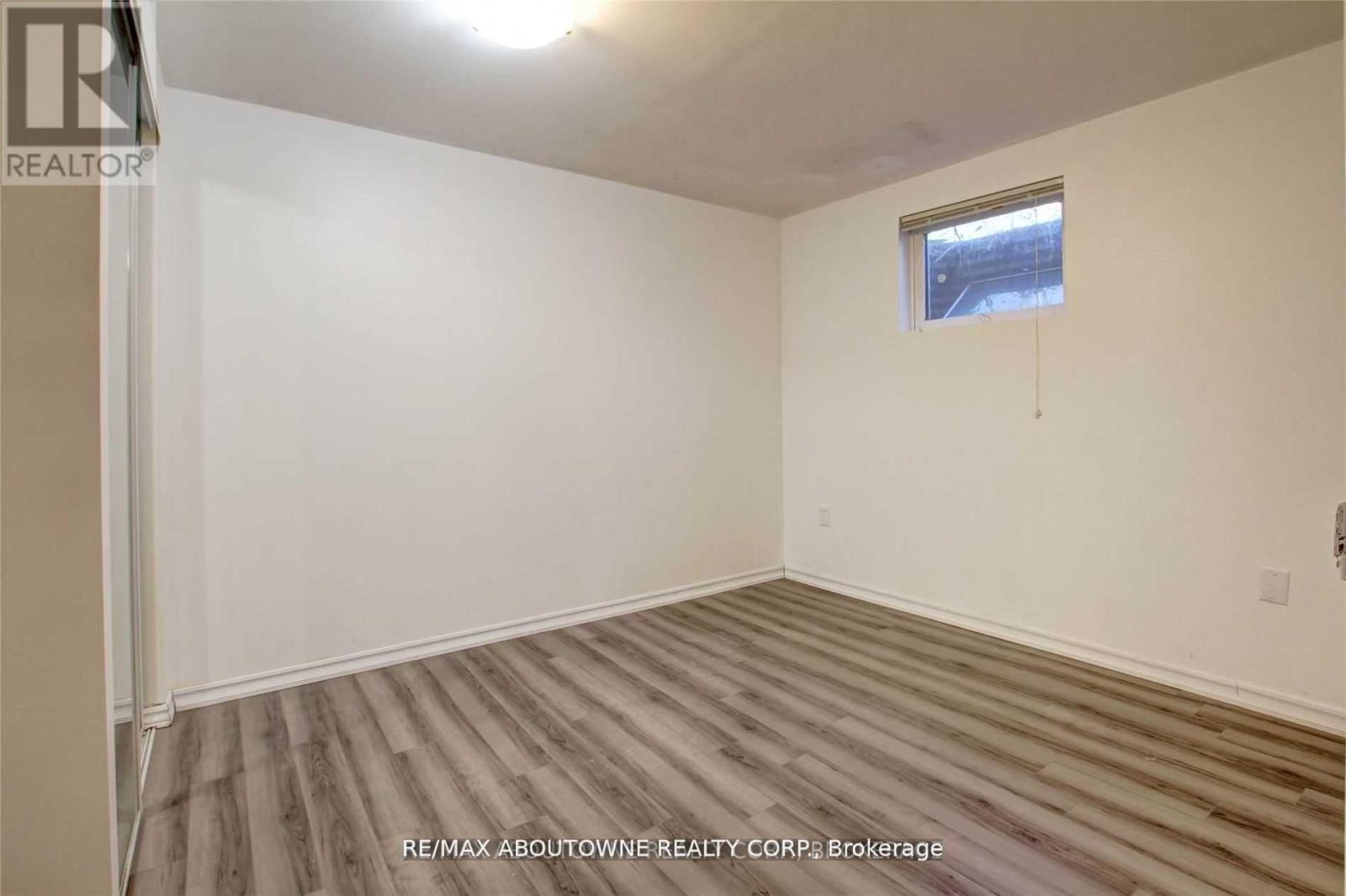 A room with wooden flooring and a window with a view of a building outside.