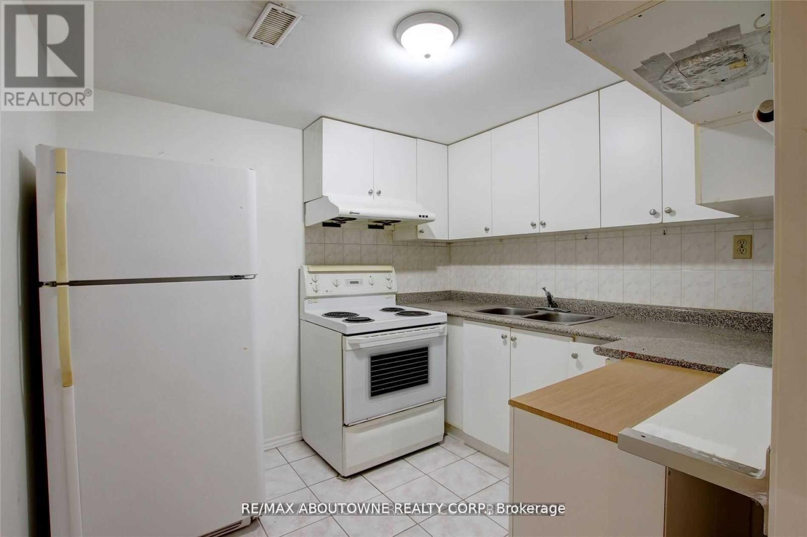 A white refrigerator is in a kitchen with white cabinets.