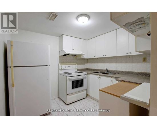 A white refrigerator is in a kitchen with white cabinets.
