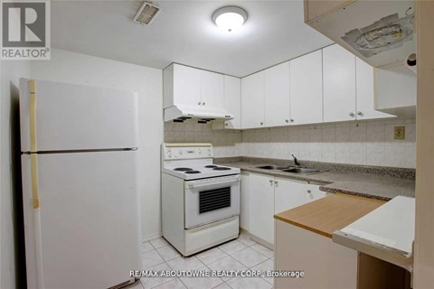 A white refrigerator is in a kitchen with white cabinets.