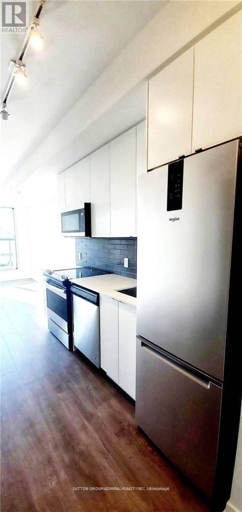 A modern kitchen with white cabinets and a stainless steel refrigerator.