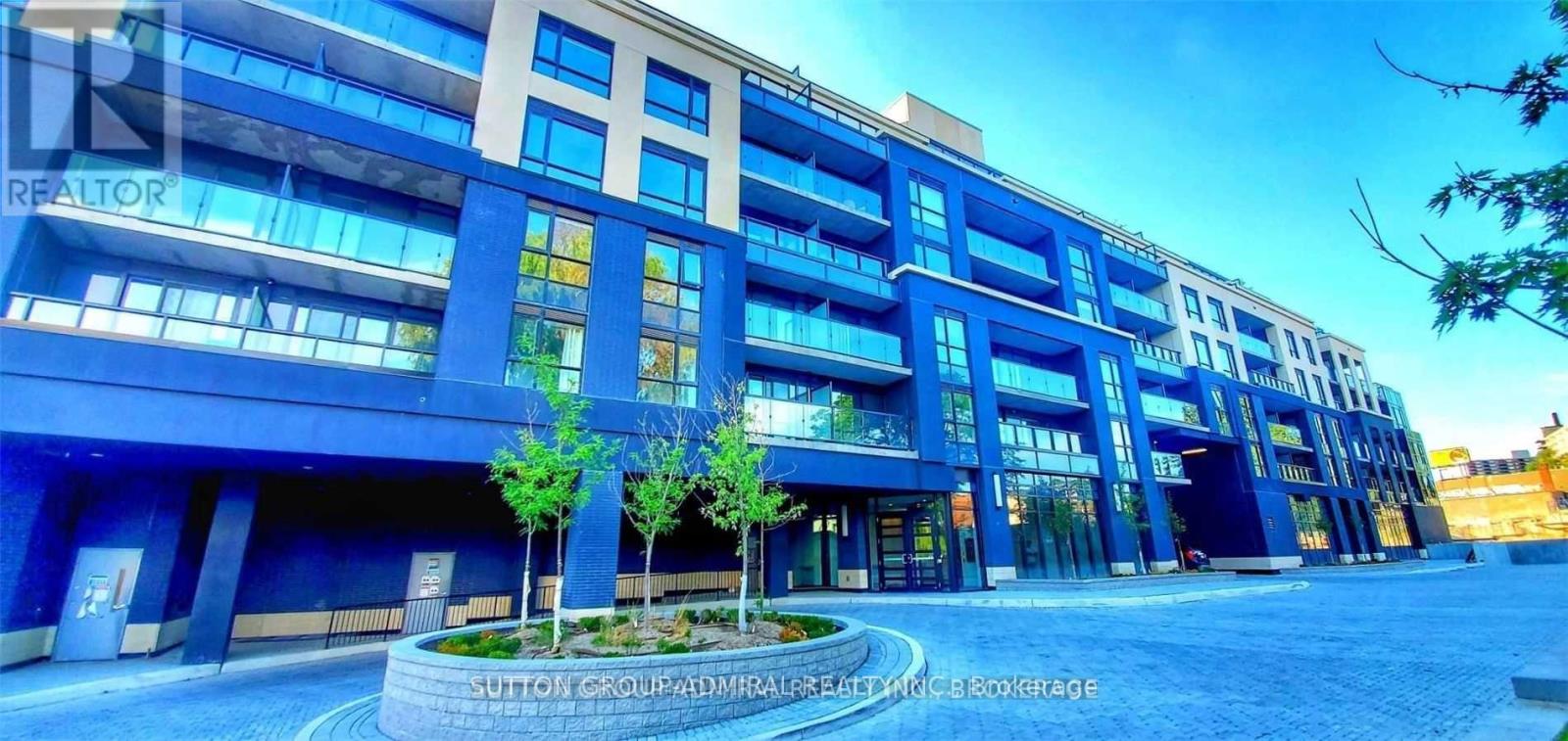 A modern building with a blue and white facade and a circular planter in front.