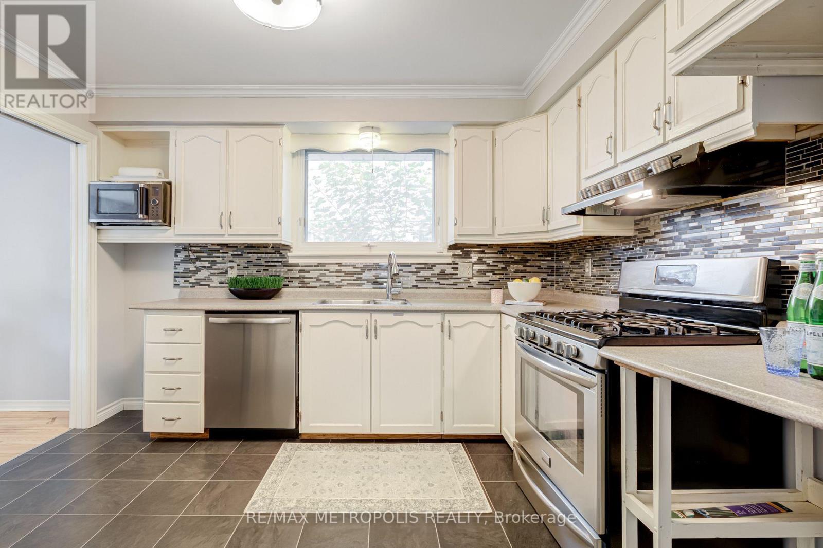 A kitchen with white cabinets and a stone backsplash.