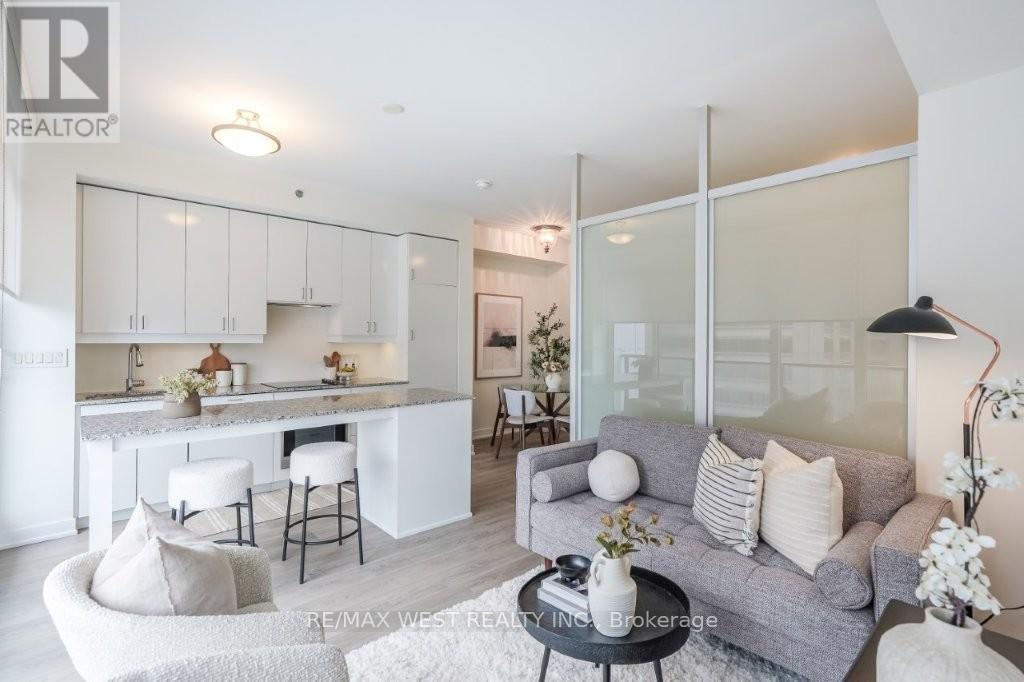 A modern living room with a grey couch and a kitchen area in the background.