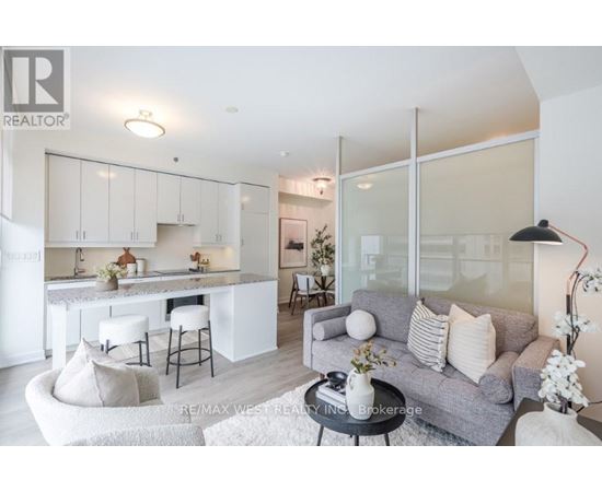 A modern living room with a grey couch and a kitchen area in the background.